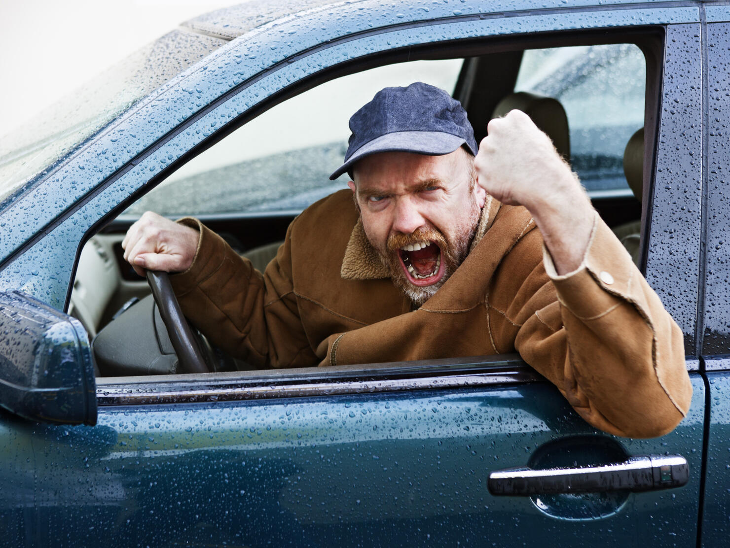 Furious male driver shakes his fist out of car window