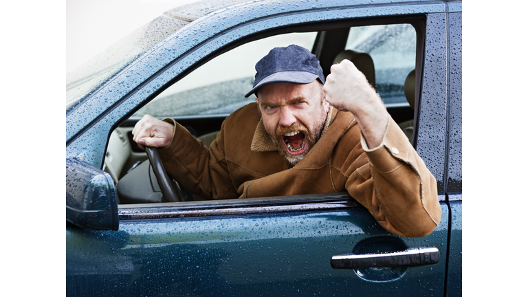 Furious male driver shakes his fist out of car window