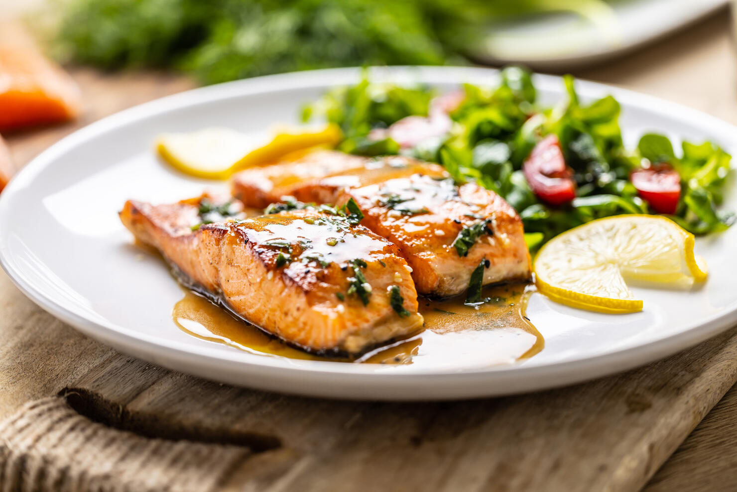 Two juicy baked salmon fillets with lettuce and tomatoes, topped with demiglas sauce.
