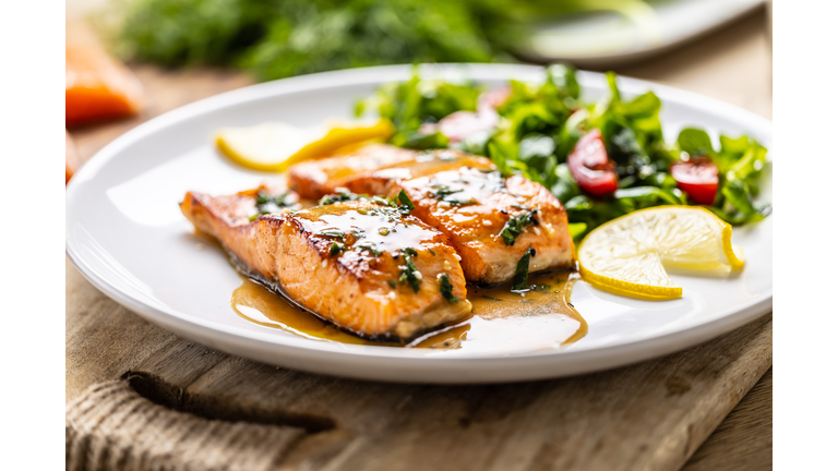Two juicy baked salmon fillets with lettuce and tomatoes, topped with demiglas sauce.
