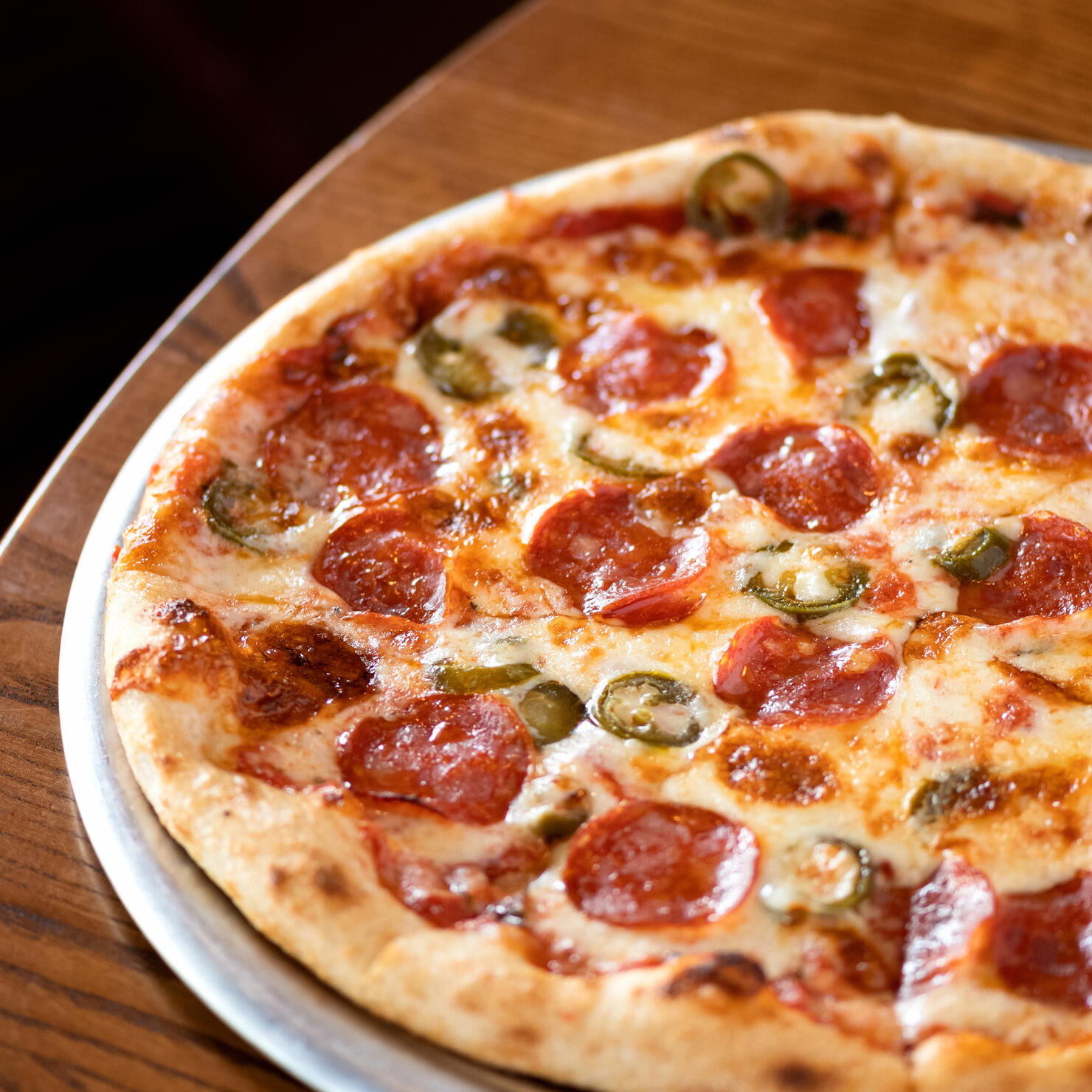 Traditional Italian pizza with pepperoni, cheese, pepper on wooden table. Italian fod. Top view . Close-up. Soft focus.