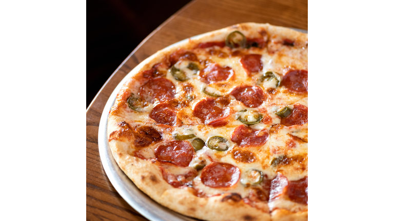 Traditional Italian pizza with pepperoni, cheese, pepper on wooden table. Italian fod. Top view . Close-up. Soft focus.