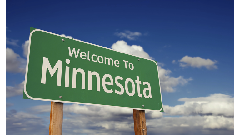Welcome to minnesota green road sign over blue sky with some clouds