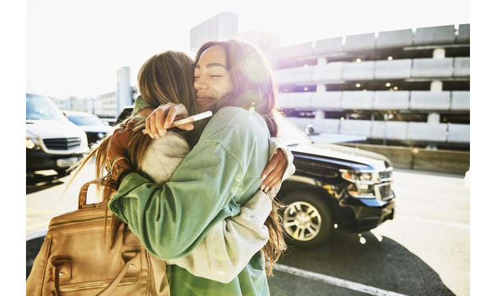 Medium shot of mother and daughter hugging curbside at airport