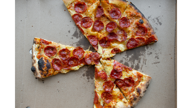 Delicious Italian pizza in a pizza box and a delivery box, on the table in a pizzeria. Sliced pizza slice with tomatoes, pepperoni sausage and cheese. The concept of unhealthy lifestyle, overeating, junk food, fast food. Delivery to your home or work.