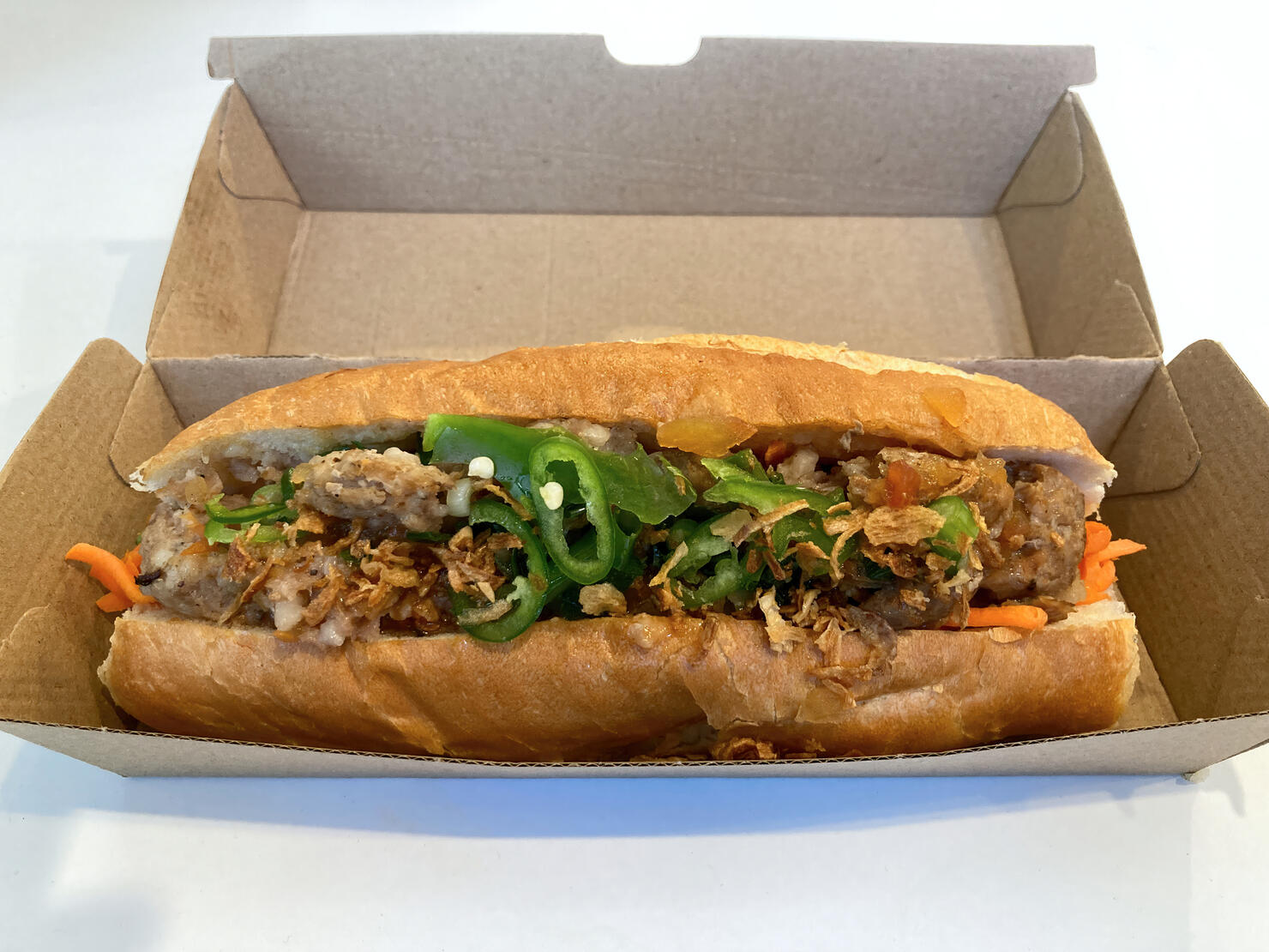 Pork meatball banh mi sandwich in a cardboard takeout box