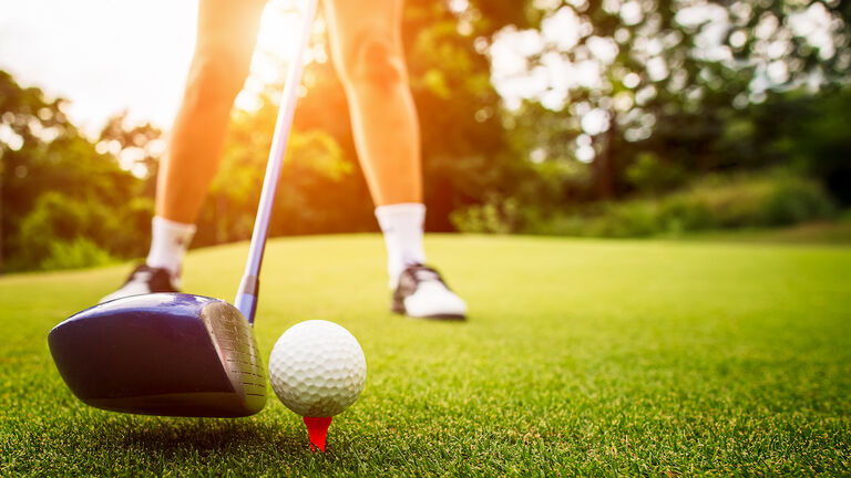 Golfer putting the ball into the hole.