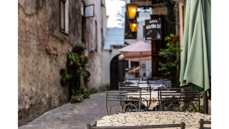 View of old cozy cafe in old city. Wooden tables and chairs in an outdoor cafe