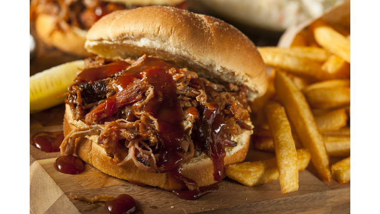 Barbeque pulled pork sandwich and fries on wooden board