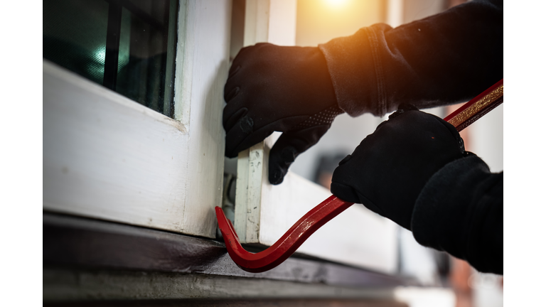 dangerous masked burglar with crowbar breaking into a victim's home door,concept