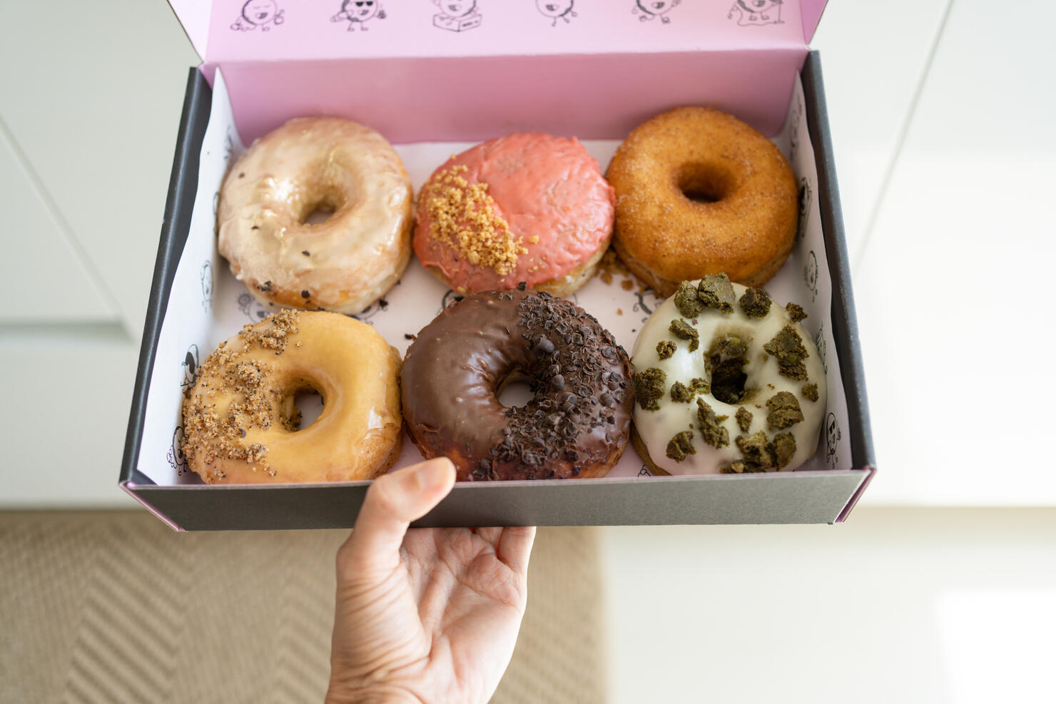 Woman holding box with doughnuts, close-up