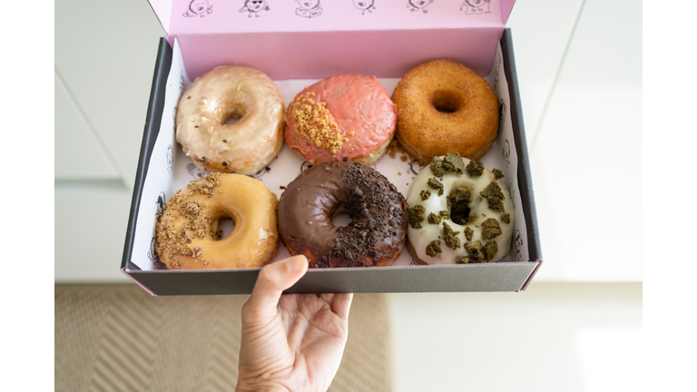 Woman holding box with doughnuts, close-up