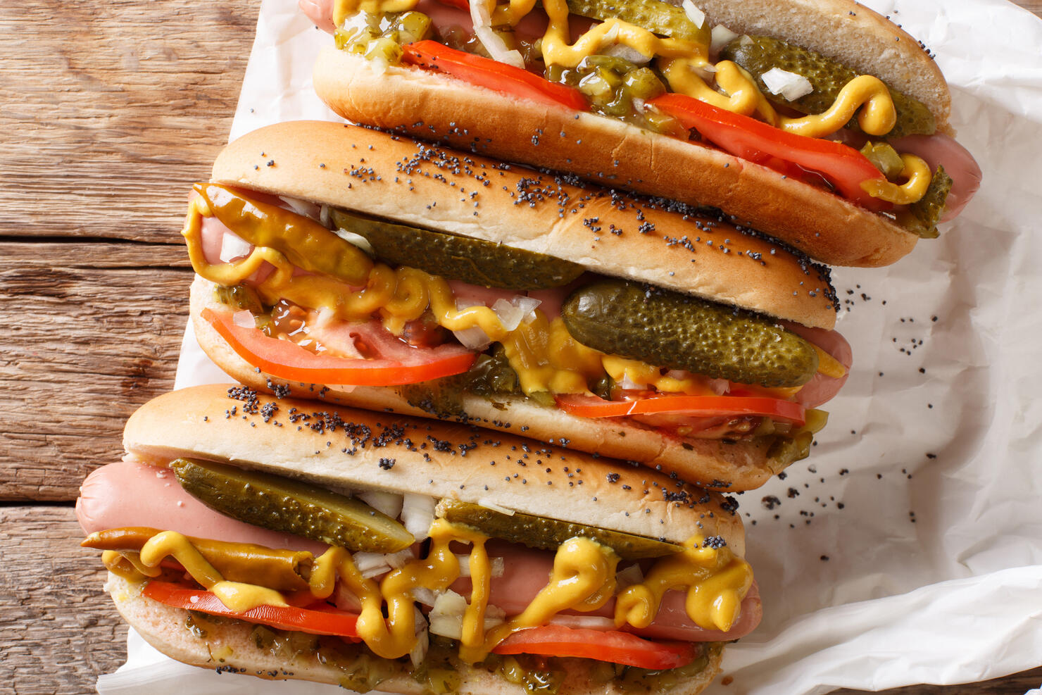 Homemade Chicago style hot dogs with mustard, tomatoes, pickled cucumbers, onions and relish close-up. Horizontal top view