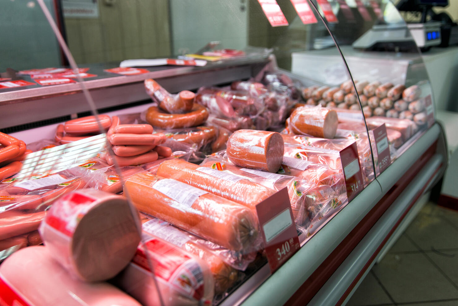 Counter with boiled sausage in store. Refrigerator shelves with different meat products