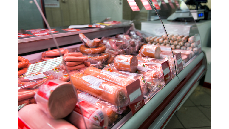 Counter with boiled sausage in store. Refrigerator shelves with different meat products