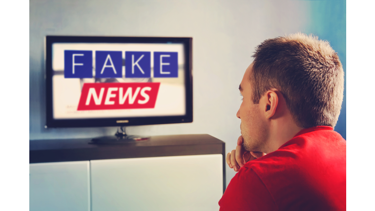 lies of tv propaganda mainstream media disinformation, A fake news report. viewer is watching TV and doesn't believe in fake news. man closes his eyes not to watch the lies on TV.