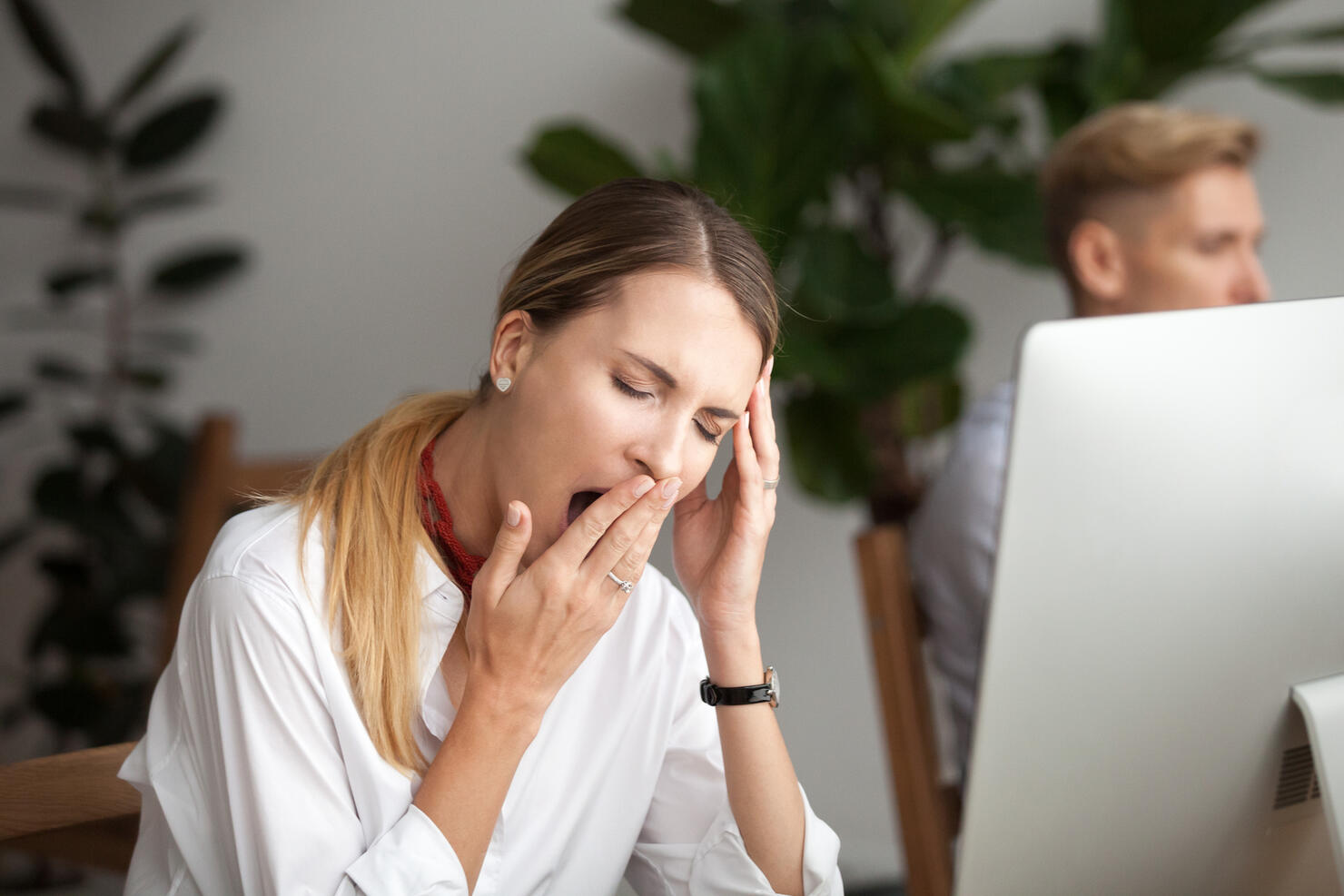 Bored tired businesswoman yawning at workplace feeling lack of sleep