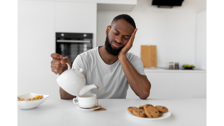 Black man pouring coffee away from cup spilling hot drink