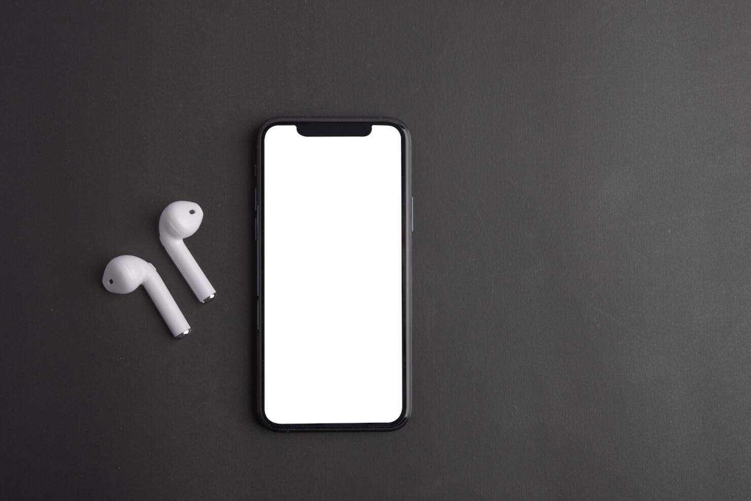 White wireless bluetooth earphones or headphones and smartphone over black background. Close up. Copy space.