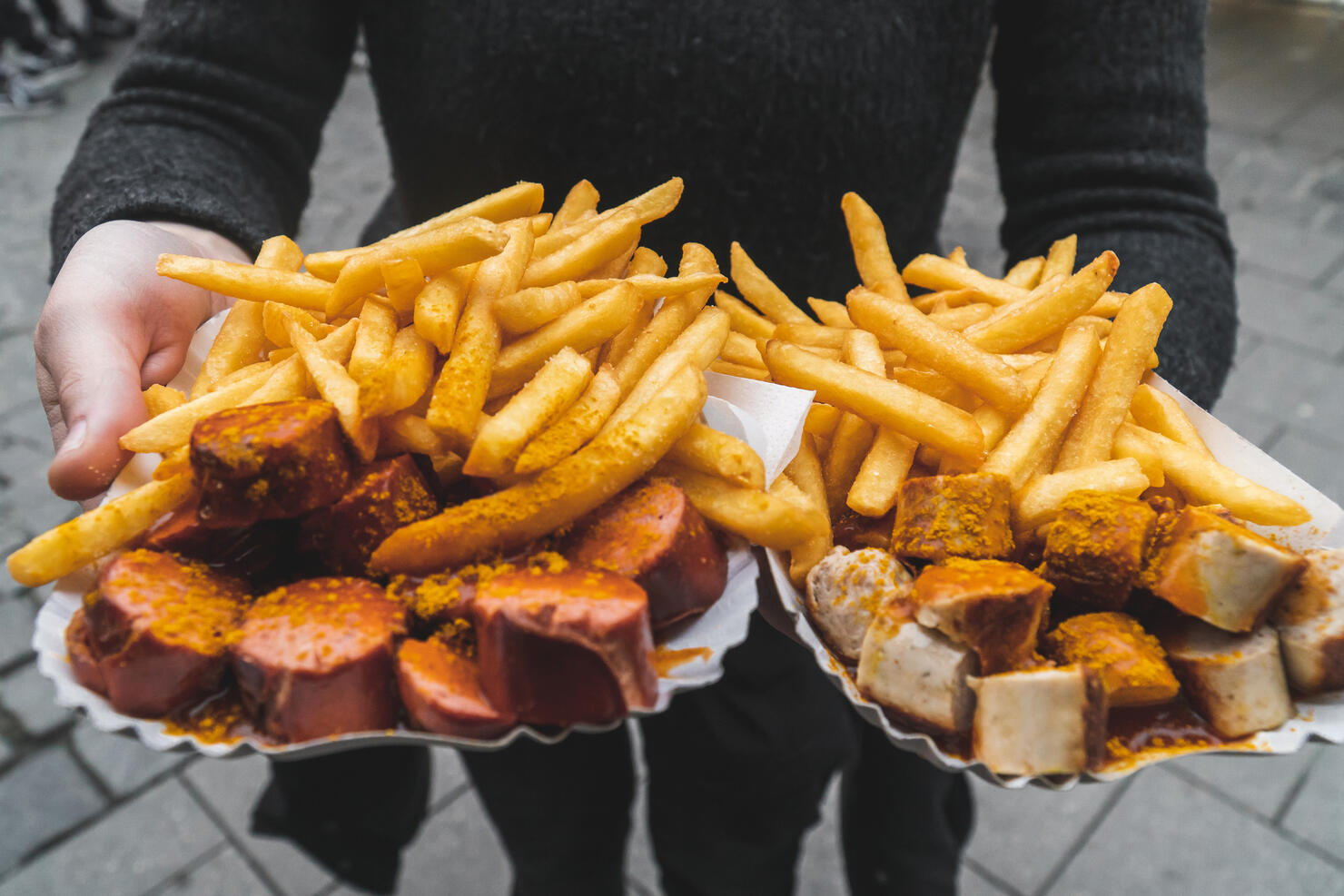 Woman hands holding traditional red and white curry wurst and french fries at Viktualienmarkt food market in Munich, Victuals Market