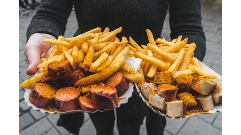 Woman hands holding traditional red and white curry wurst and french fries at Viktualienmarkt food market in Munich, Victuals Market