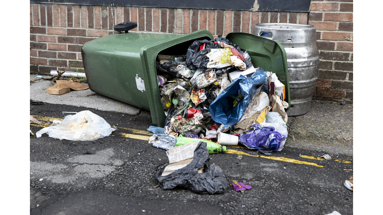 Overturned wheelie bin with spilled rubbish in the residential back street of a northern England city