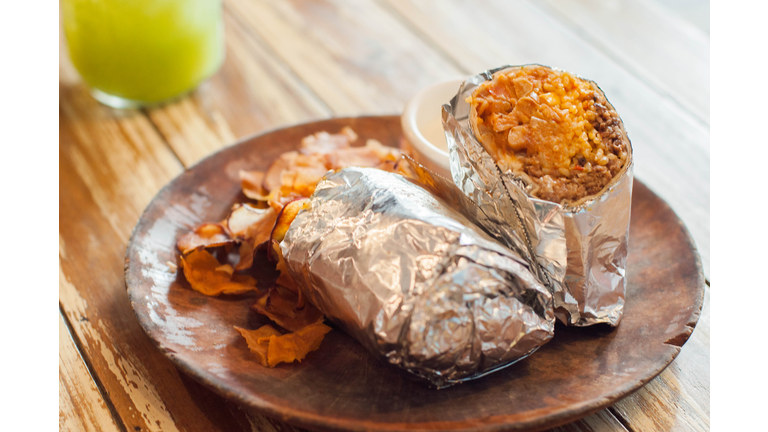 A close-up view of Mexican Burrito with sweet potato chips on a wooden table
