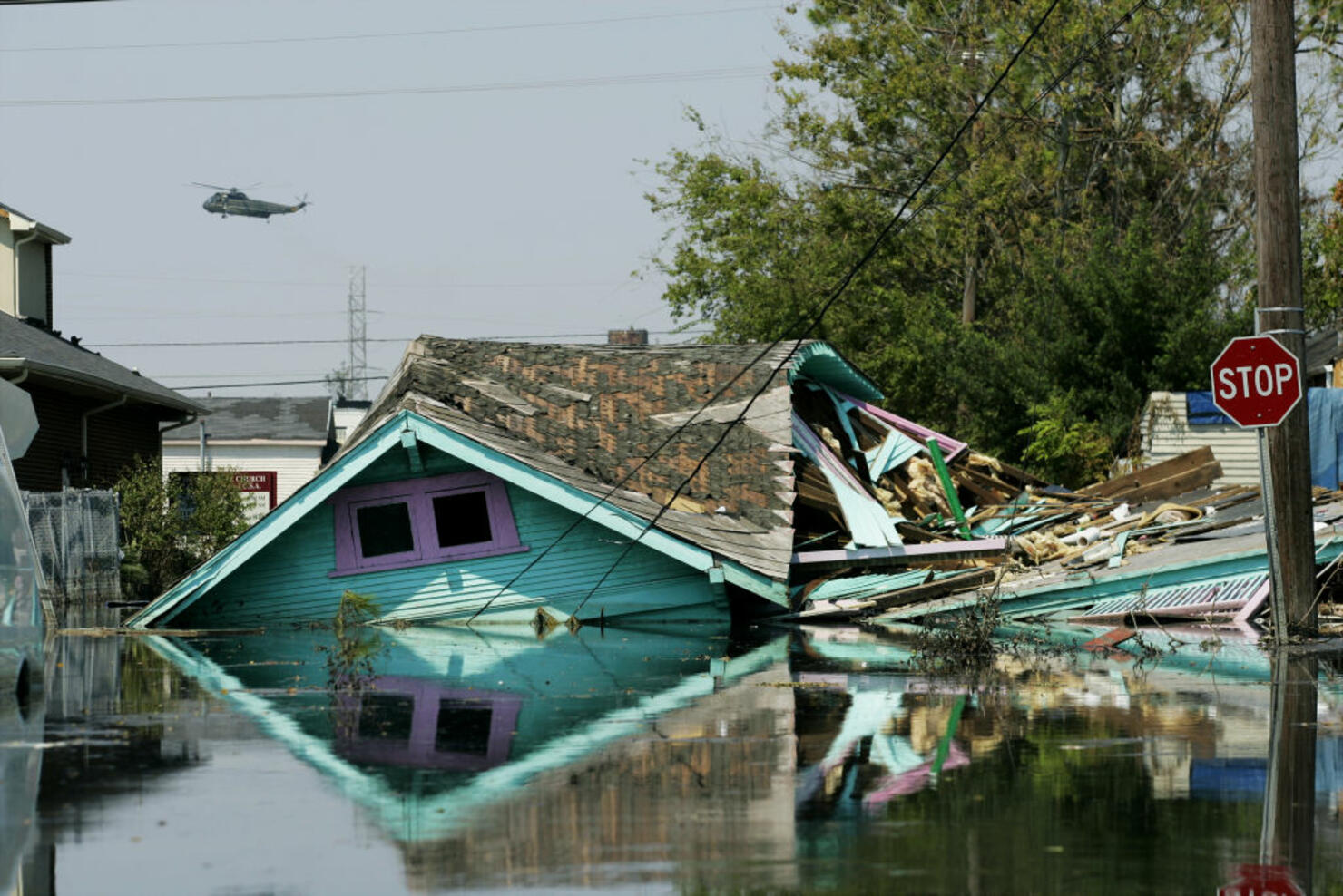 Military helicopter buzzes over the splintered remains of a 