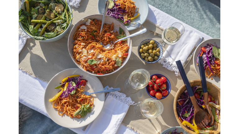 Dining table with plates and bowls of food outdoors.