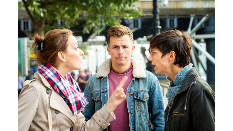 Young man dismayed as his girlfriend argues with ex