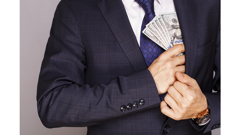 Businessman putting money in suit jacket pocket