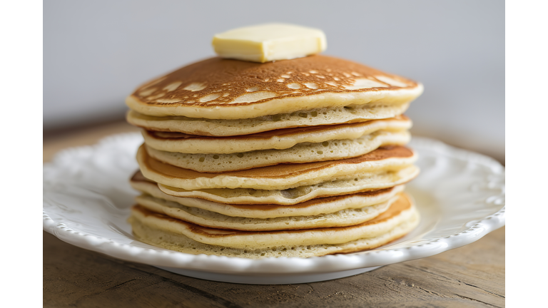 A stack of buttered pancakes on a white plate