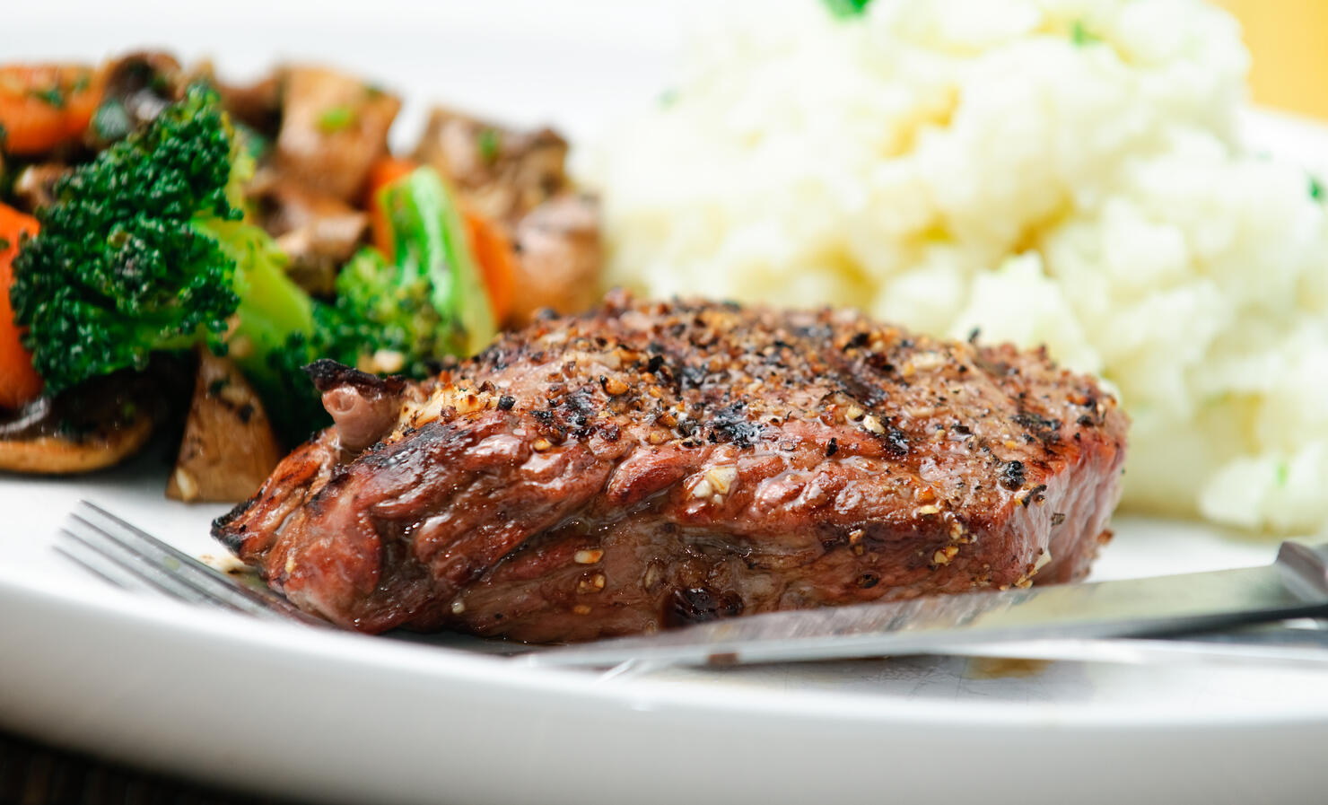 A steak dinner with mashed potatoes and vegetable medley