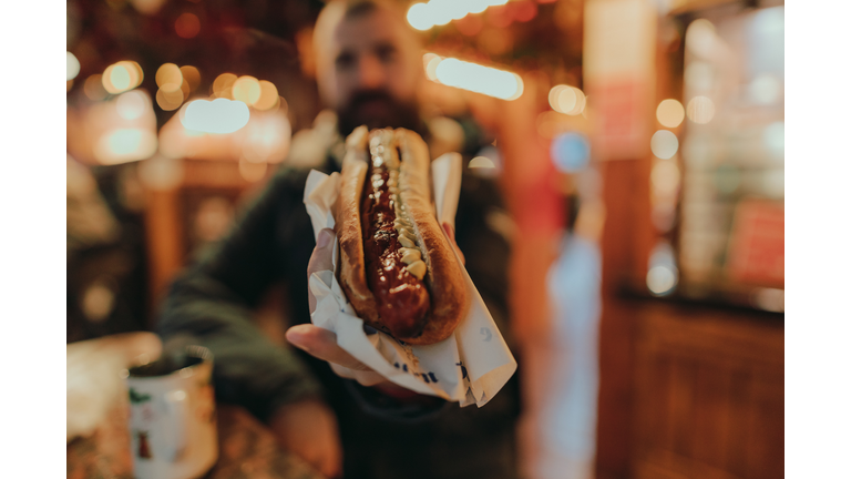 Man eating a sausage hot dog and enjoying a Christmas market