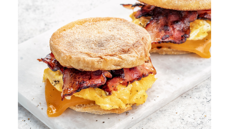 English muffin, egg, ham, and cheese breakfast sandwich on a cutting board