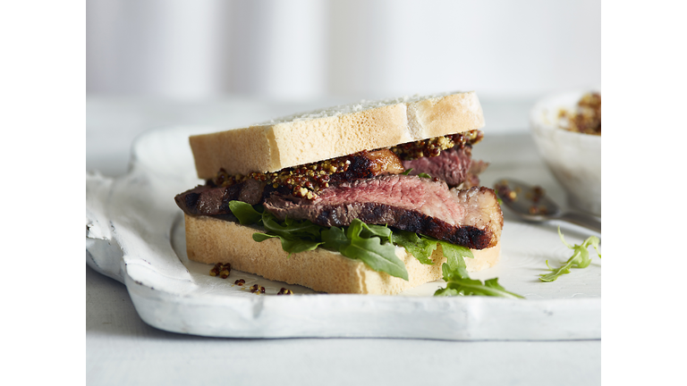 Steak sandwich with mustard on tray