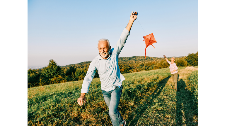 woman man outdoor senior couple happy lifestyle retirement together smiling love kite run nature mature