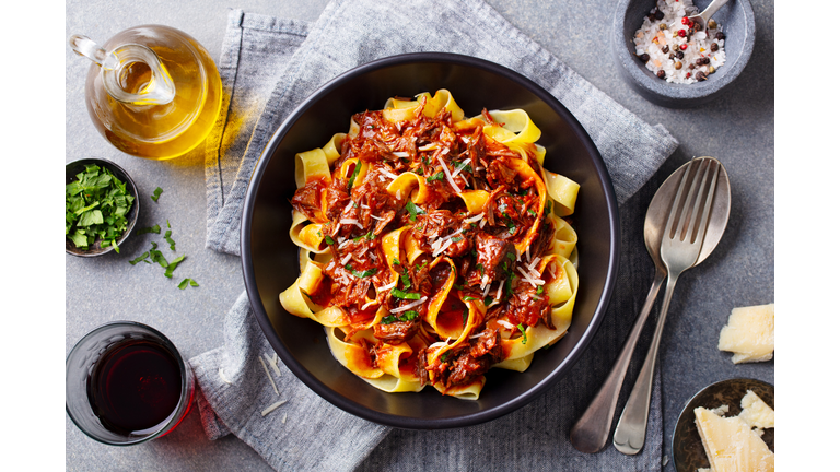 Pasta fettuccine with beef ragout sauce in black bowl. Grey background. Close up. Top view.