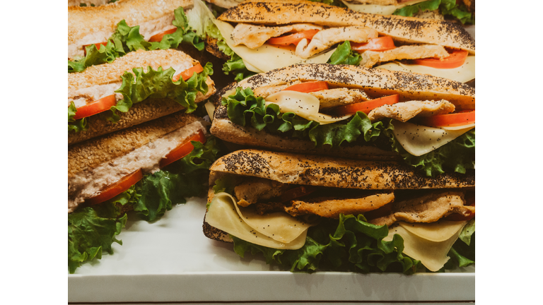 Assortment of chicken sandwiches with cheese, tomatoes, and lettuce on display
