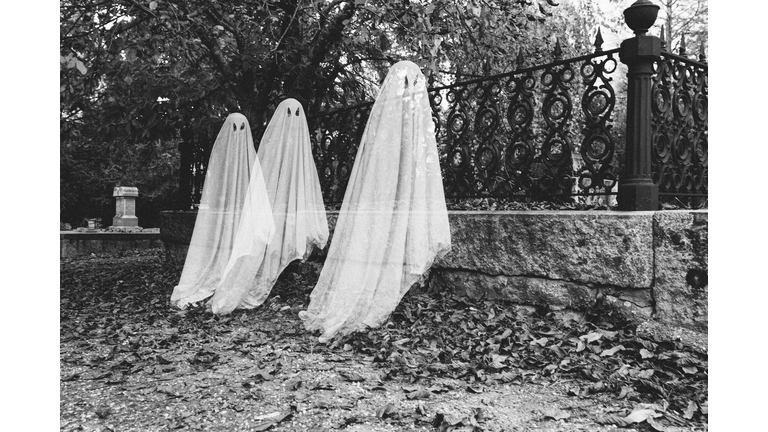 Double exposure of boys in ghost costumes at cemetery during Halloween