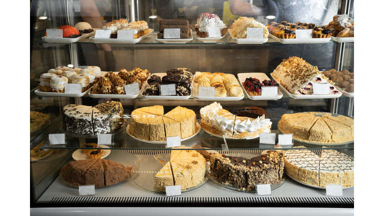 Pastry shop glass display with selection of cream or fruit cake, bakery shop with various flavors of cake