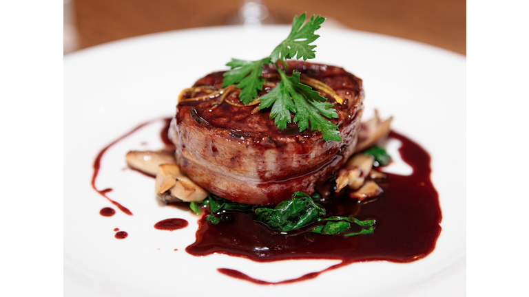 Tenderloin steak wrapped in bacon with red sauce and garlic