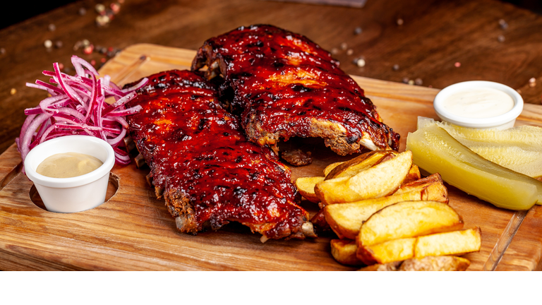 Fried ribs air fryer in marinade, with tartar sauce on a wooden board. With French fries in a rustic way and vegetables. concept of a beautiful serve in a restaurant or in a cafe.