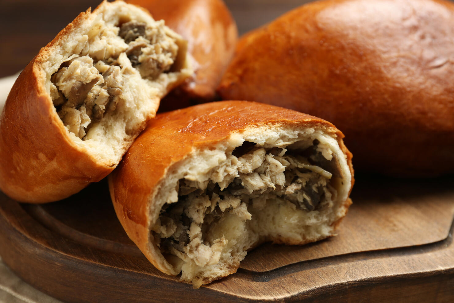 Delicious baked patties with meat and mushrooms on wooden board, closeup