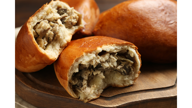 Delicious baked patties with meat and mushrooms on wooden board, closeup