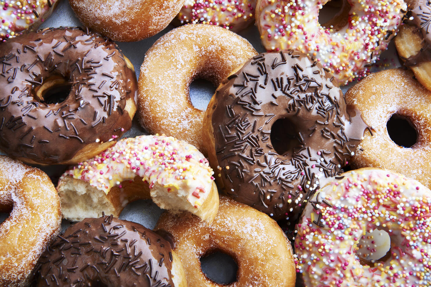 Ring doughnuts covered in icing and sprinkes