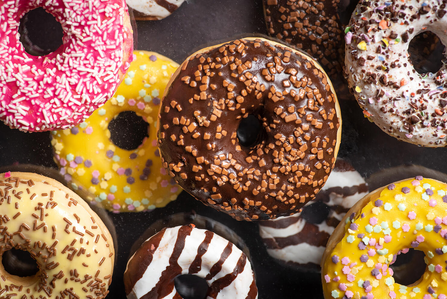 Colorful chocolate covered sweet donuts with sweet sprinkles dessert closeup top view