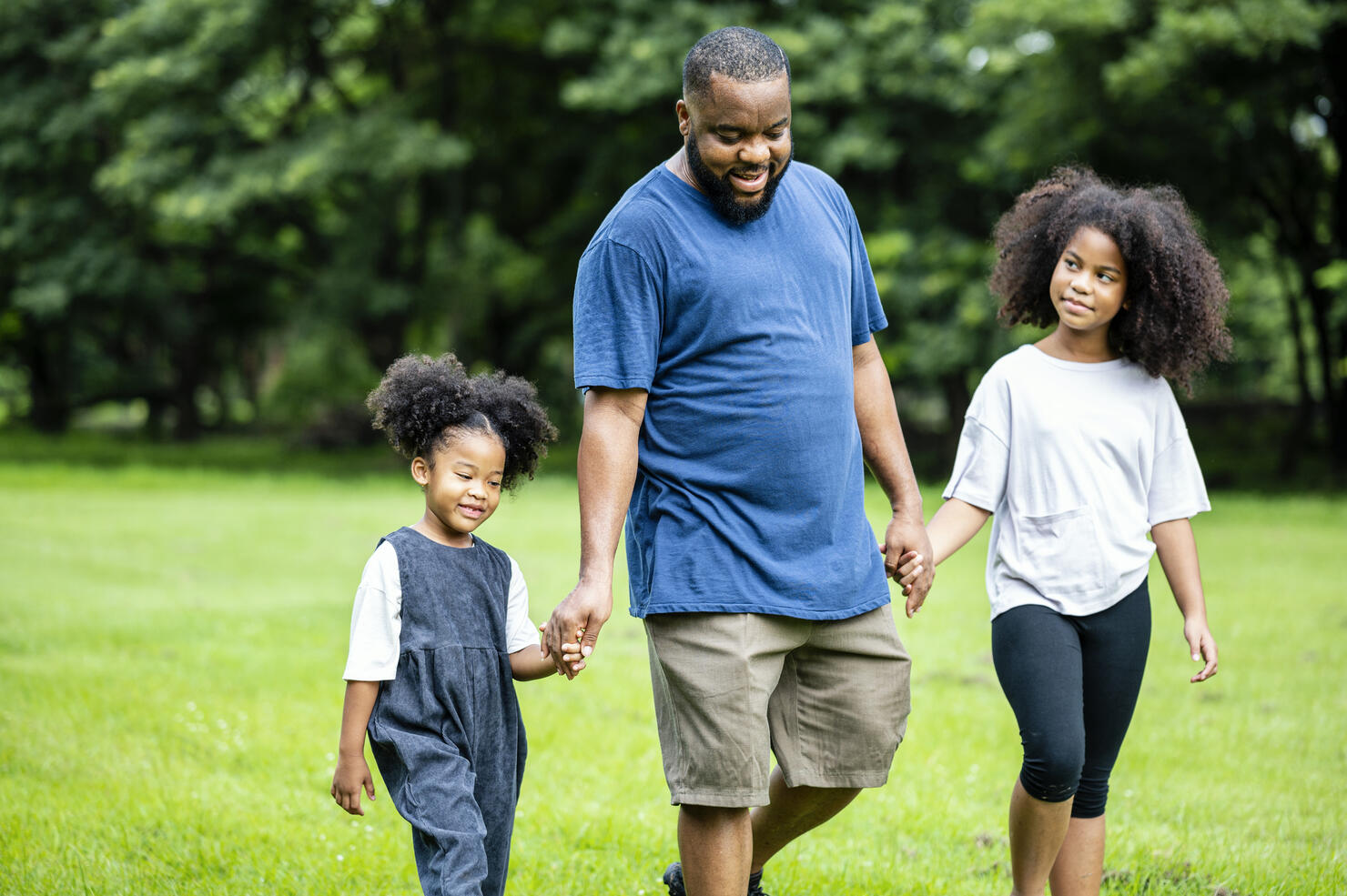 African Father and daughters walking in the public park together. Simple living, Leisure Activity.