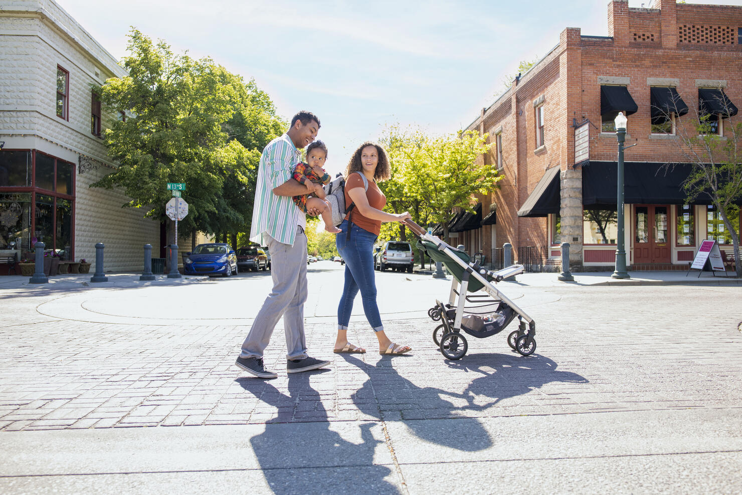 Young family strolling with baby daughter on city street