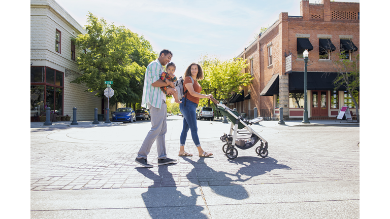 Young family strolling with baby daughter on city street